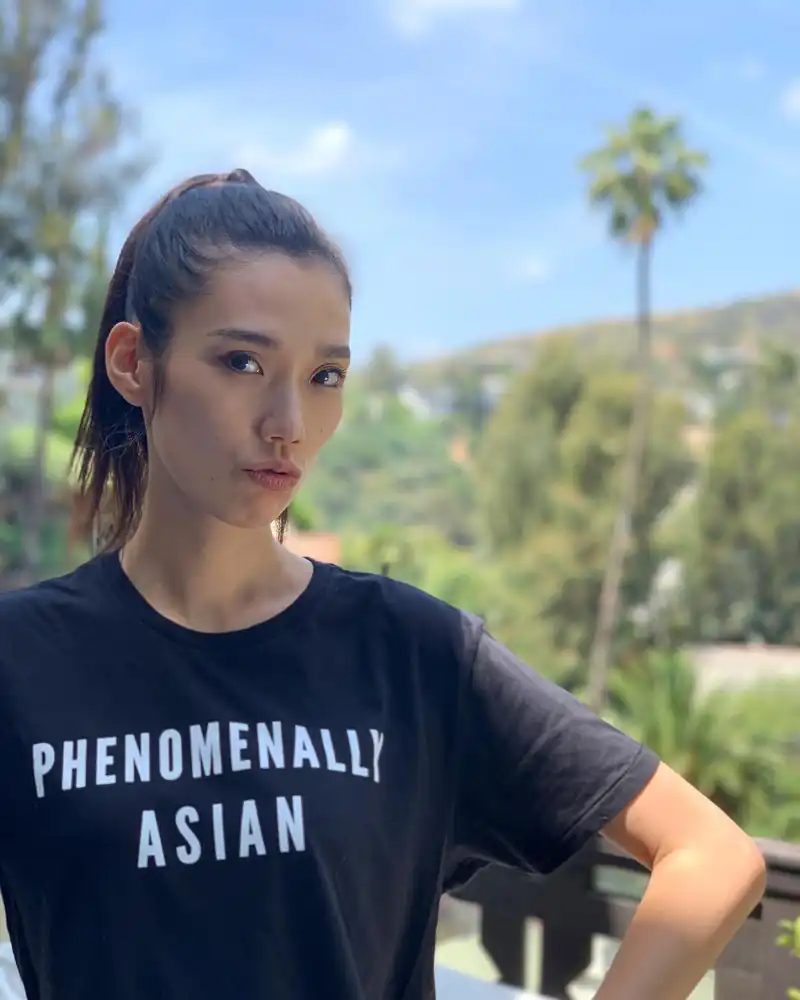 Photo of Tao Okamoto in a T-shirt that has the text "Phenomenally Asian"
