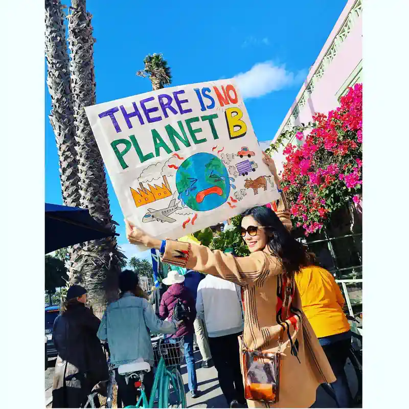 Photo of Tao Okamoto from a climate change movement rally where she is holding a poster that says, "There is no planet B"
